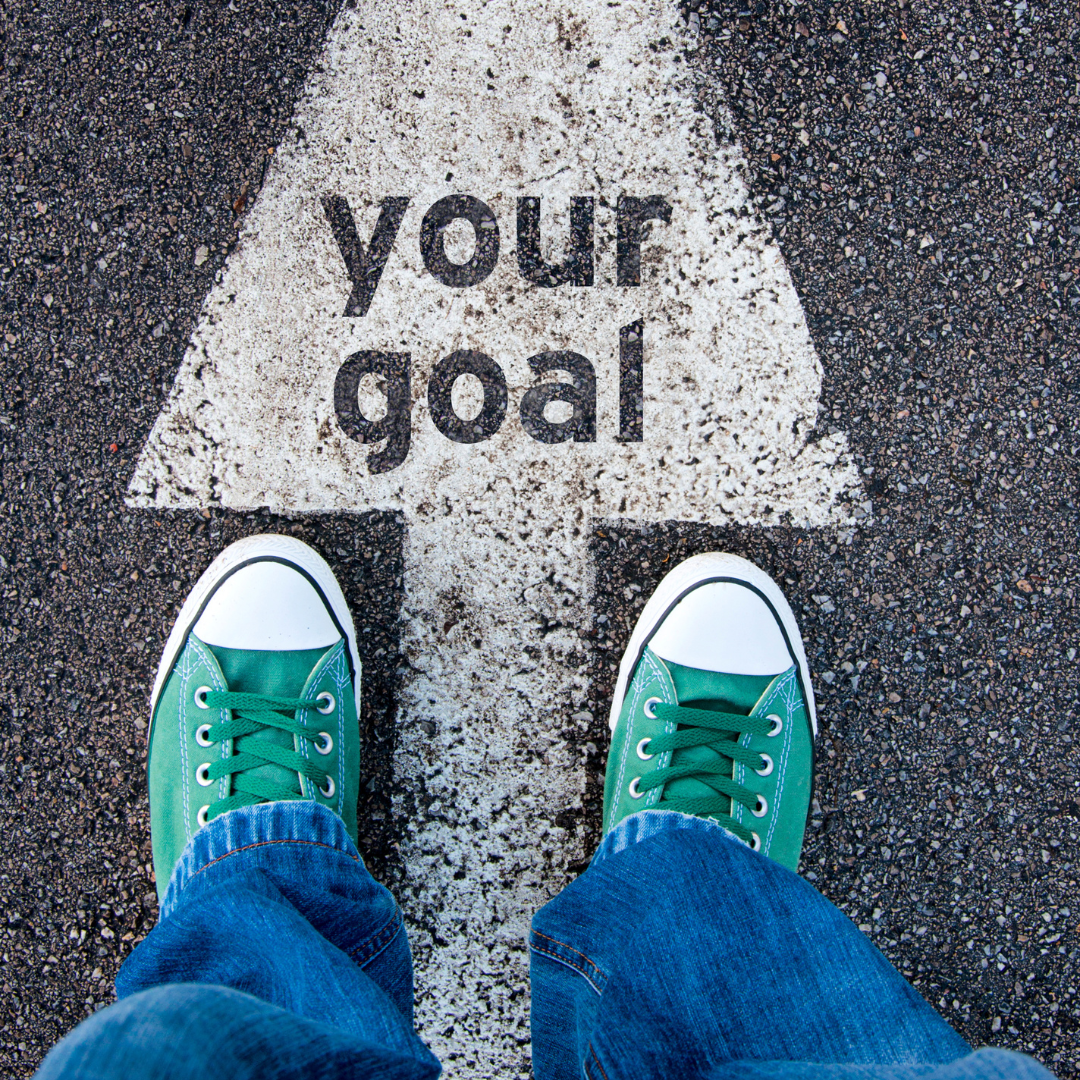 person standing on painted arrow that says "Your Goals"