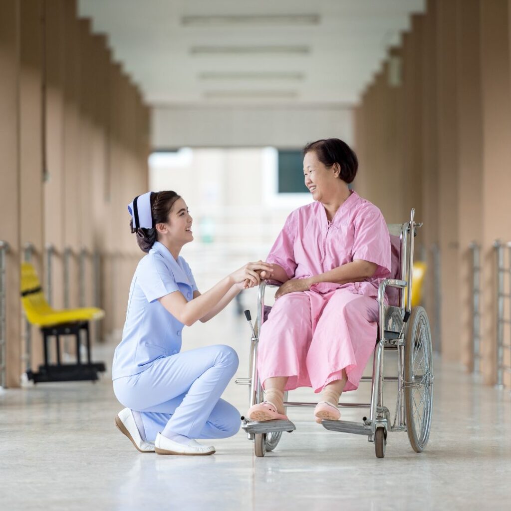 nurse kneeling in front a patient in wheelchair