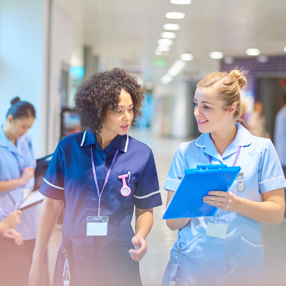nurses with clipboards talking in hallway