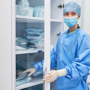 A nurse in full scrubs getting something from a cabinet