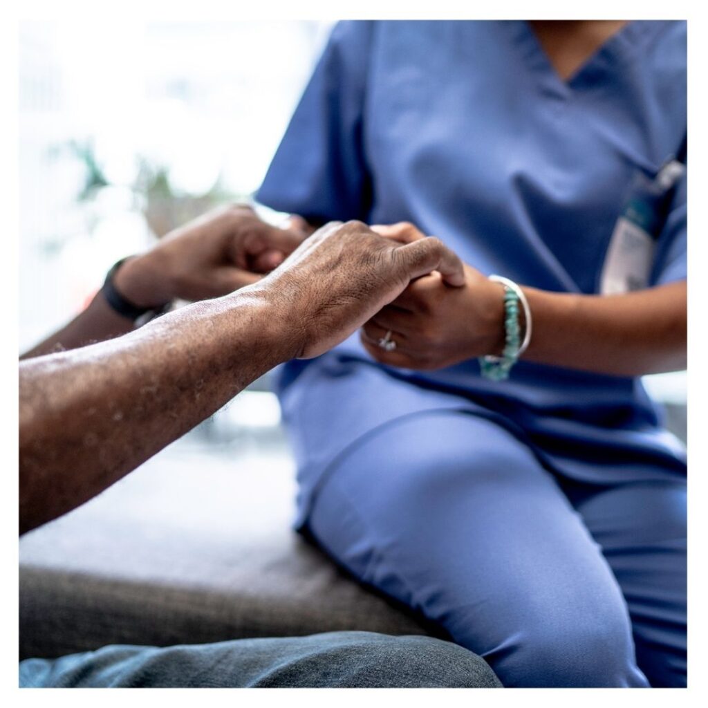 A nurse holding a patients hands