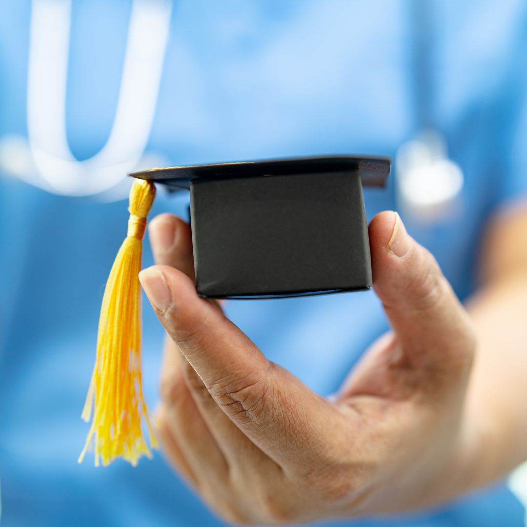 nursing holding small graduation cap