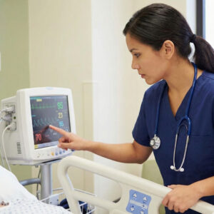 A nurse intently checking patient vital signs on a bedside monitor