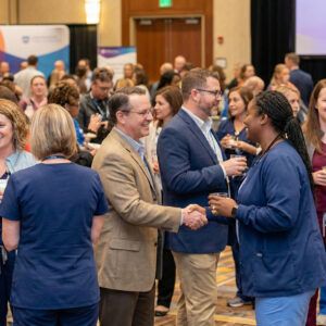 Professionals mingling and shaking hands at a nursing conference networking event